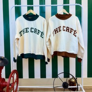 Café Sweaters in both green and brown trim hanging up